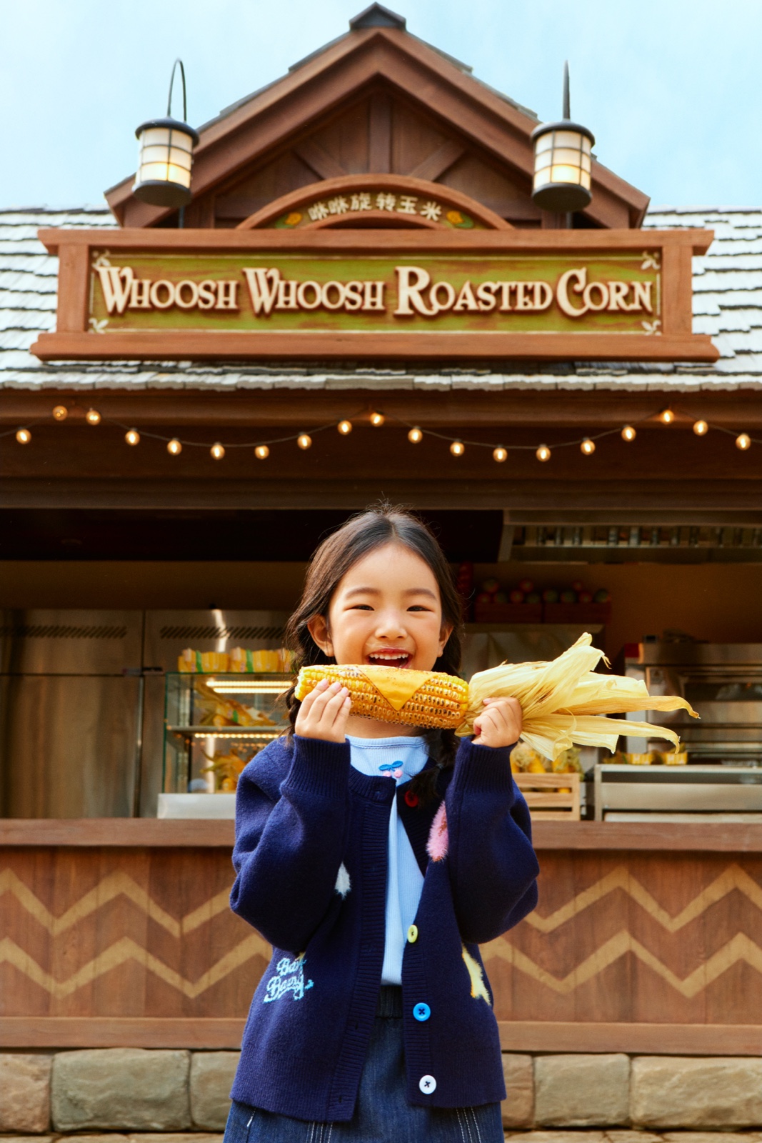 A guest holding roasted corn at a themed snack stand