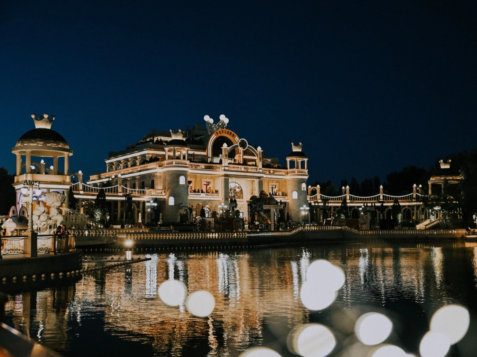 POP LAND castle lit at night, reflected in the lake